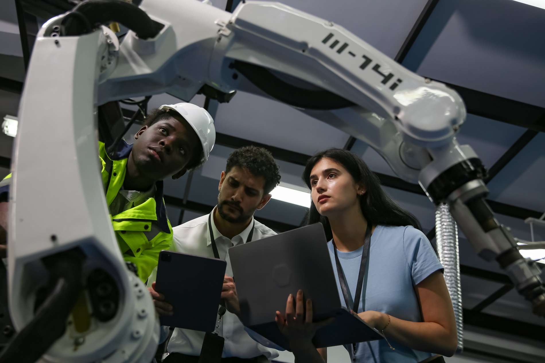 Robotic Arm engineer check on equipment in its with software of Artificial Intelligence Unit. Engineers inspecting and check up machine of the automated arms machine robots at factory. Engineer working automatic robotic arm machine in factory. technician worker maintenance robot. Technology concept.